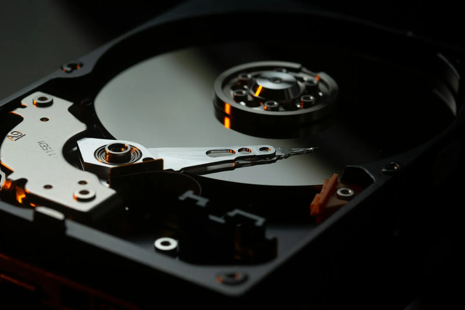 An open hard drive showing the platter and read/write arm